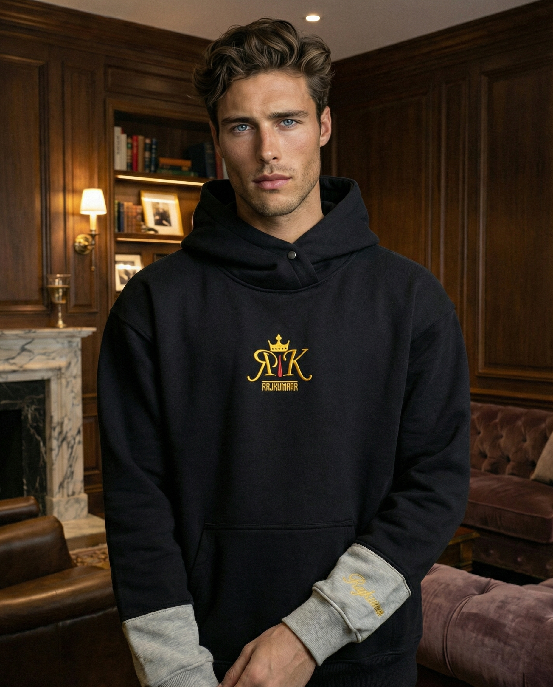 Model wearing a black hoodie with Rajkumarr logo on the chest, standing indoors.