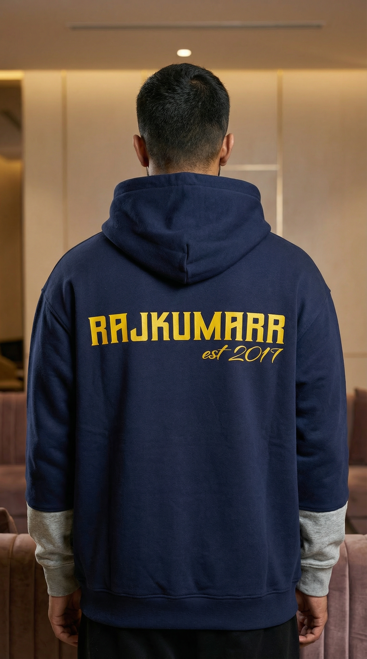 Model wearing a navy blue Rajkumarr hoodie, rear view